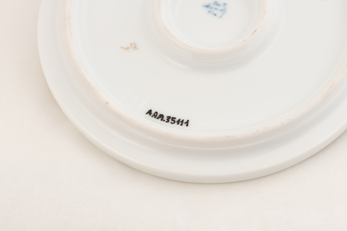 En porselenstallerken med påmalte blomster og to sommerfugler.