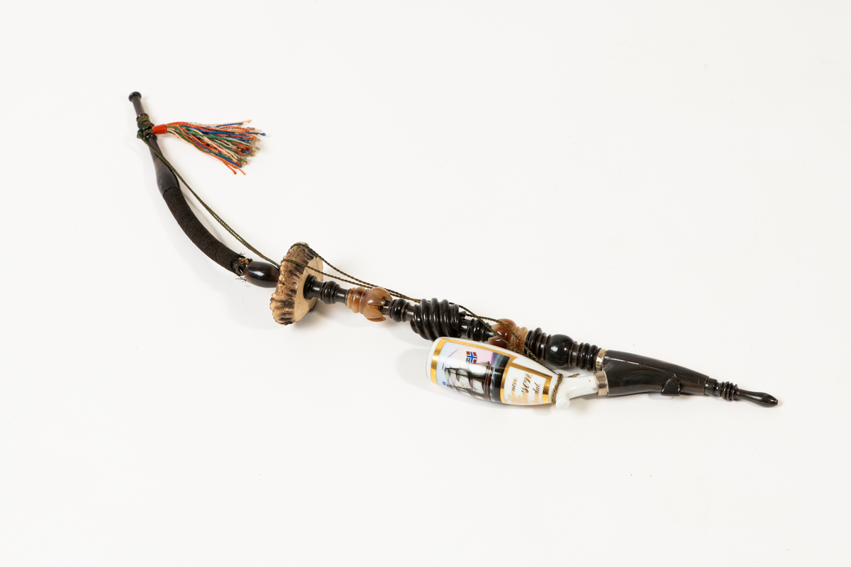 Lang pipe med tilknytning til Merdøgaard og Larssønfamilien. Pipen består av mange ulike materialer og har et stort pipehode i porselen. Pipehodet er dekorert med et lite maleri av skipet Nordstjernen med det norske flagg i masta med unionsmerket med det svenske flagget i det ene hjørnet, også kalt "sildesalaten". Slike flagg var vanlige før unionsoppløsningen i 1905. Rundt maleriet er det malt med streker med gullmaling. Under maleriet står det "Nordstjernen.", "J. Peterson." og "Arendal". Pipeskaftet består av mange materialer som horn/bein som er dreid og utskåret på en dekorativ måte som stikker ut.  Mot midten av pipen er det en skive av horn før pipeskaftet fortsetter opp mot munnstykket i et rør av metall og tekstil.  Ved munnstykket henger den en fargerik dusk og det er festet en snor som går dobbelt fra toppen av pipen og ned til pipehodet. Pipen har noen skader og var fortsatt full av tobakk da den ble registrert.