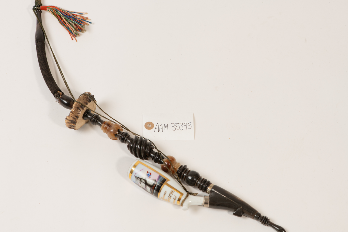 Lang pipe med tilknytning til Merdøgaard og Larssønfamilien. Pipen består av mange ulike materialer og har et stort pipehode i porselen. Pipehodet er dekorert med et lite maleri av skipet Nordstjernen med det norske flagg i masta med unionsmerket med det svenske flagget i det ene hjørnet, også kalt "sildesalaten". Slike flagg var vanlige før unionsoppløsningen i 1905. Rundt maleriet er det malt med streker med gullmaling. Under maleriet står det "Nordstjernen.", "J. Peterson." og "Arendal". Pipeskaftet består av mange materialer som horn/bein som er dreid og utskåret på en dekorativ måte som stikker ut.  Mot midten av pipen er det en skive av horn før pipeskaftet fortsetter opp mot munnstykket i et rør av metall og tekstil.  Ved munnstykket henger den en fargerik dusk og det er festet en snor som går dobbelt fra toppen av pipen og ned til pipehodet. Pipen har noen skader og var fortsatt full av tobakk da den ble registrert.