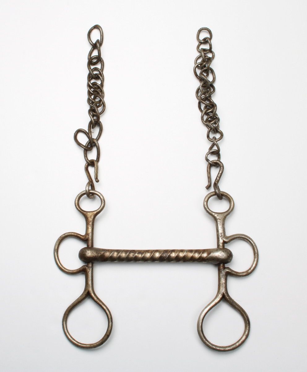 Kraftigt stångbett med räfflad stång. Parerstång med remöglor och tömringar. Kindkedja avbruten på mitten.