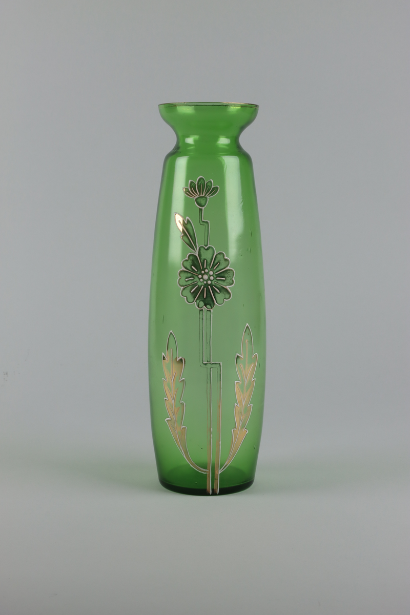 Vas av grönt glas. Spolformad kropp med en utvikt mynning upptill. Mynningen dekorerad med en förgylld kant och smal bård. Mitt fram på vasen dekor med blommor, stjälkar och blad i förgylld emalj. Allt dekor i guld och vitt mot en grön grund.