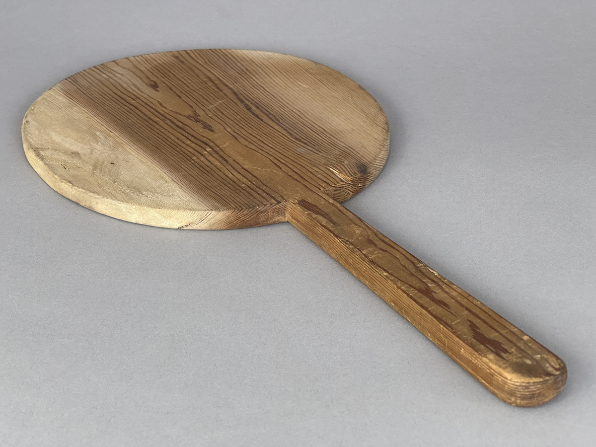 Oval brödspade eller skärbräda med skaft i trä.
