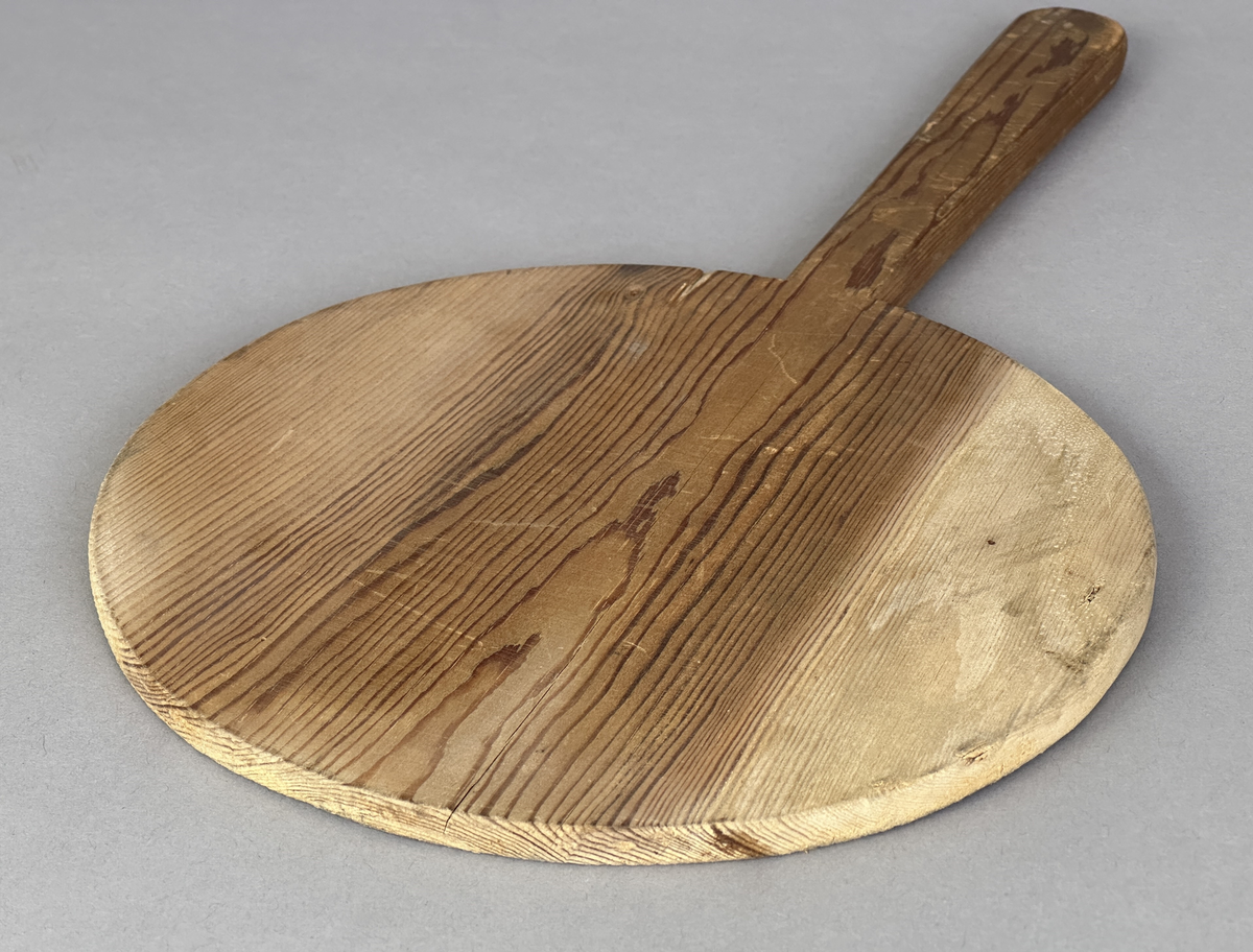 Oval brödspade eller skärbräda med skaft i trä.