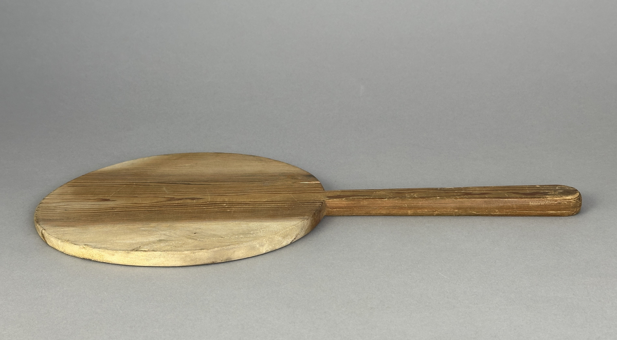 Oval brödspade eller skärbräda med skaft i trä.