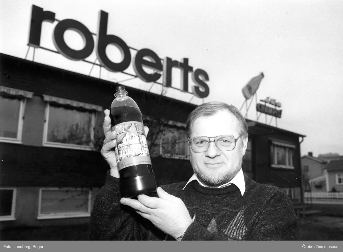 Julmust. 
Göran Roberts med en flaska julmust framför Roberts bryggeribyggnad i Örnsro. 
12 december 1992.