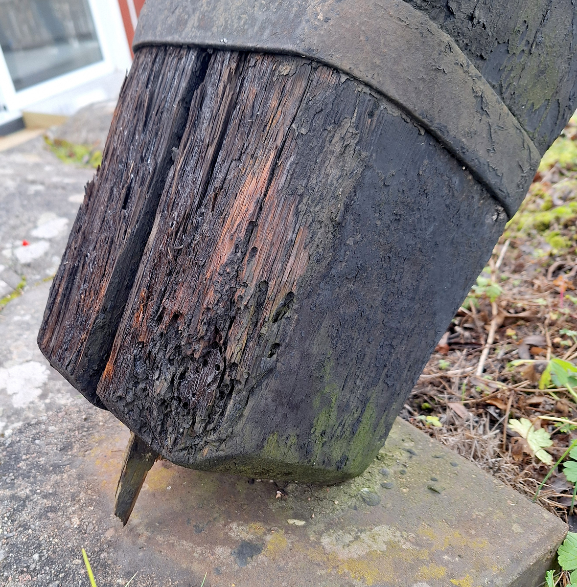 Stockankare. Trästock med fyra järnband samt en skyddskåpa i metall över ändträet på övre delen. Stockens två delar hålls ihop med fyra kilade trädymlingar. Stocken är på vissa partier mycket sliten. Schackel i röringen.
