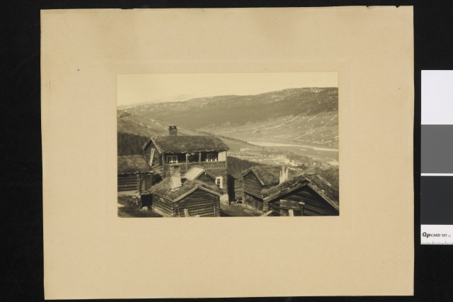 Skaar Gård med flere trebygninger i en klynge i et fjellandskap.