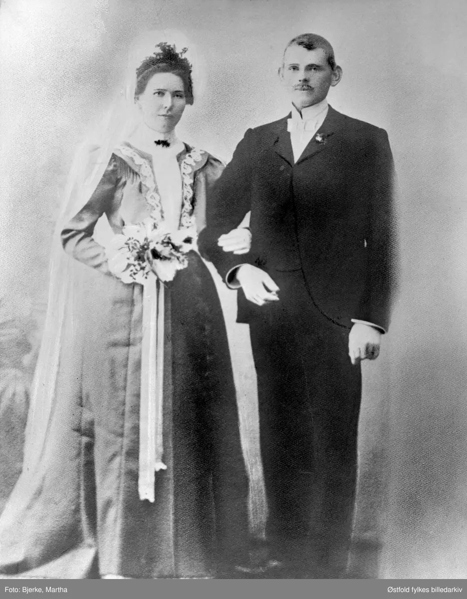 Bryllupsportrett av Josefine Marie Johansen Åsen og Ole Lunde fra Varteoig, mars 1907. Josefine (1883-1971) og Ole (1878-1963) drev gården Lunde, også kalt vest "Lønne", i Varteig. Bildet er tatt dagen etter bryllupet. Brudeparet rodde ca. 1 time for å komme til fotografen i Sarpsborg. Josefine var fra Rakkesatd (?).