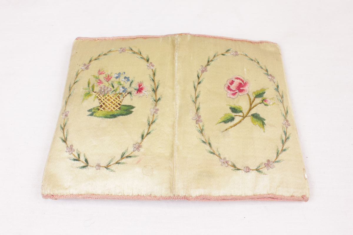 Sammenleggbar bok i brodert silkestoff med en lomme på innsiden av hver perm. På utsiden er det brodert en rose (forside) og blomster i en kurv (bakside). På innsiden er det brodert teksten "Tænk på Din Dorte gode Jens" og en jordbærplante.

I lommene er det flere sammenbrettede papirer, to med gjenstander inni:

1. En blond hårlokk pakket inn i et stykke blankt papir, antakelig fra Dorte.

2. En rød "mynt" pakket inn i et papir med håndskrift.

3. Flere fragmenter av "Musernes skaal" av Henrik Anker Bjerregaard revet ut av en bok. Teksten har samme språkdrakt som i R. Hviids visebok fra 1821, men er trykt med nyere antikvaskrift. En fornorsket versjon (f.eks. "hvor" til "hvem", "faaer" til "faar") er trykt i bl.a. "Visebog for norske Selskabskredse" (1850), "Visebok for det norske Studentersamfund" (1856) og "Harpen sang- og visesamling" av Peter Worsøe (1870).

4. Et ark med en håndskrevet versjon av "Musernes Skaal", trolig en avskrift av nevnte boksider.

5. Fire små lapper med trykte "visdoms"vers og med håndskrevne navn på mottaker og avsender. Alle er til Jens Lauritz Kjerulf og signert henholdsvis Lovise Pettersen, Lina Hjort, J. J. Hjort og [utydelig].