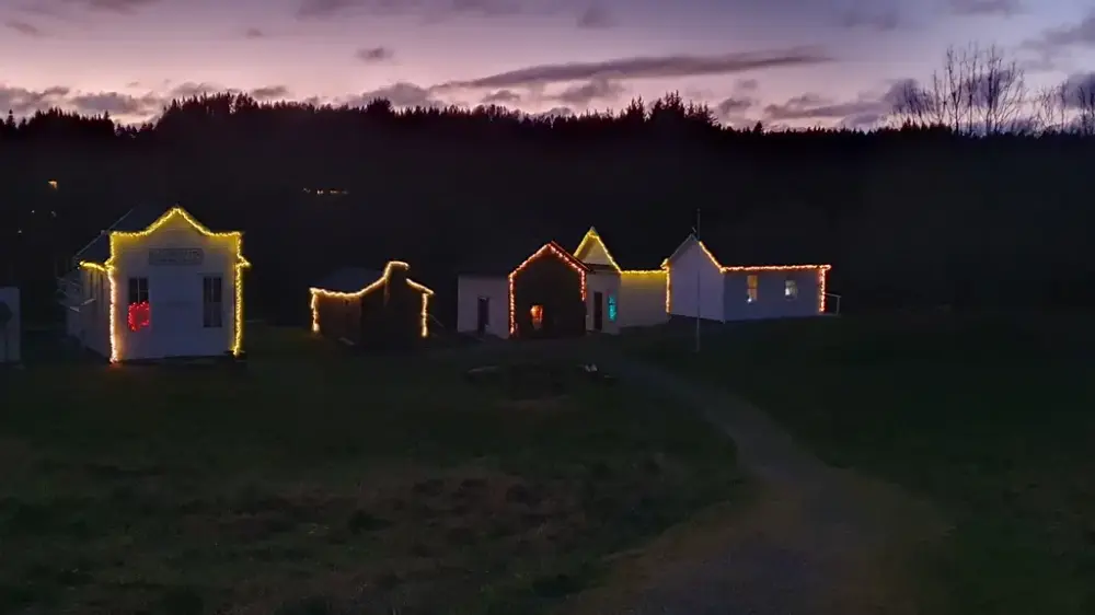 Prærielandsbyen en vinterkveld, opplyst av hvite lys i silhouetten. Rosa kveldshimmel i horisonten.