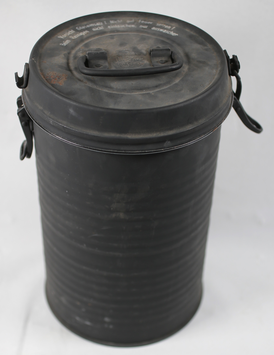 Metallbeholder med mettallokk som kan låses på to sider. Innvendig glass