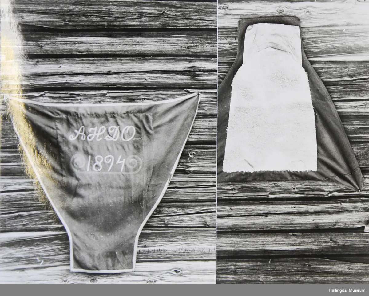 Rektangulært stykke nederst, sidene skråner ut oppover, rett øverst med avkuttede hjørner. Sammensatt av flere stykker. Kantet langs alle kanter med rødt bånd. Tekst med samme bånd. På baksida påsydd rektangulært stykke saueskinn, brettet opp og danner lomme nederst.