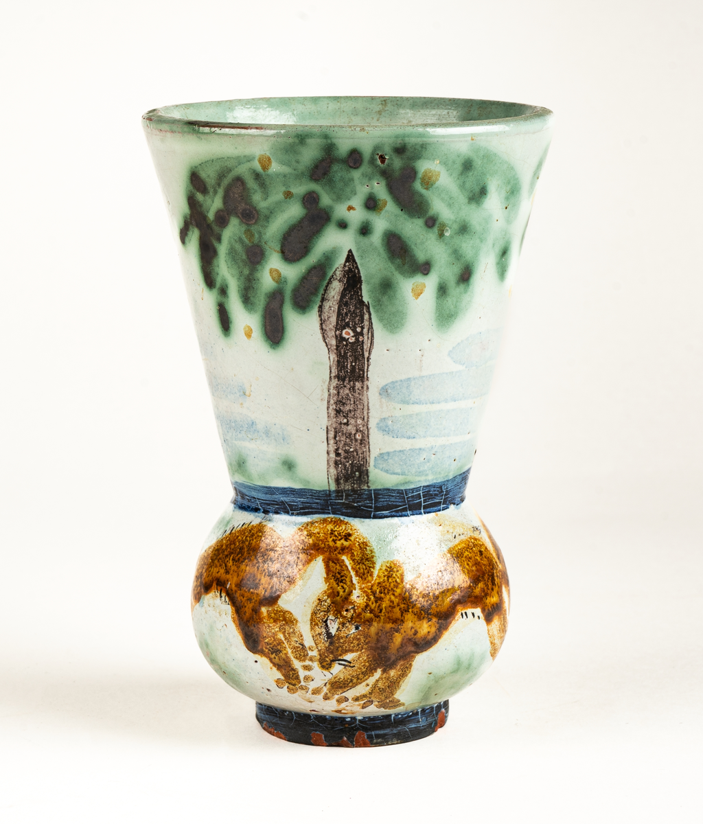 Vas, övre delen glaserad med trädmotiv i grönt, blått och brunt. Den nedre delens motiv föreställer springande ekorrar. Formgiven av Märta Willborg, 1930.