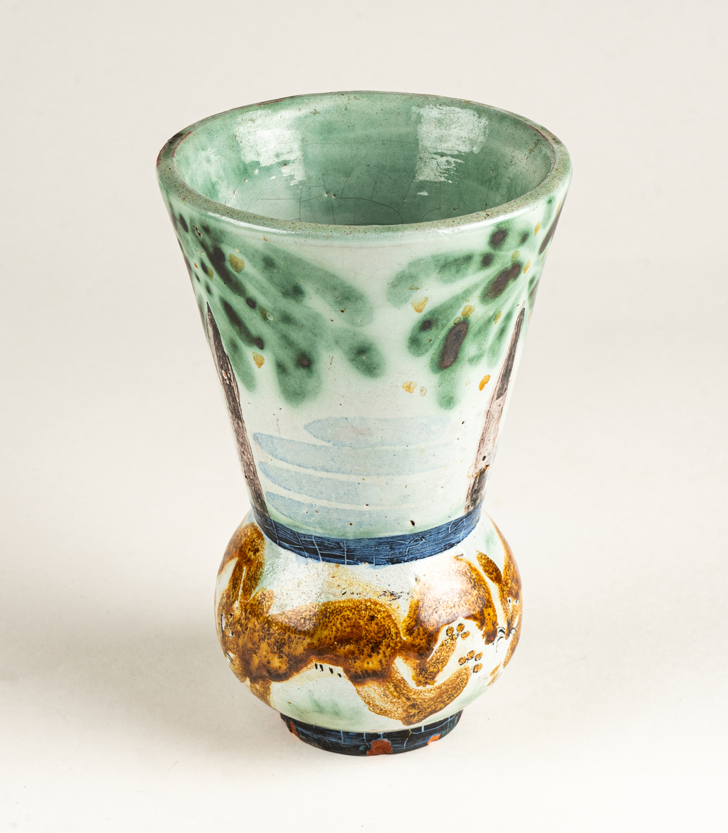 Vas, övre delen glaserad med trädmotiv i grönt, blått och brunt. Den nedre delens motiv föreställer springande ekorrar. Formgiven av Märta Willborg, 1930.