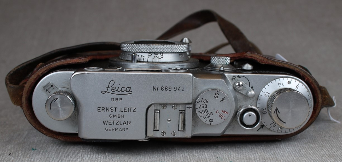 Fotografiapparat i skinntaske med bærehempe. Bruksanvisning medfølger.