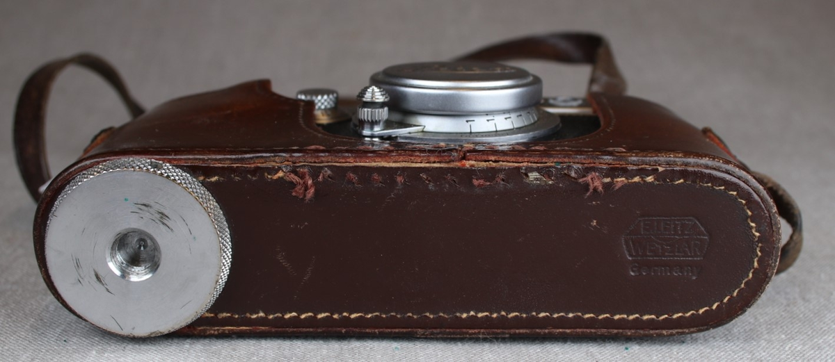 Fotografiapparat i skinntaske med bærehempe. Bruksanvisning medfølger.