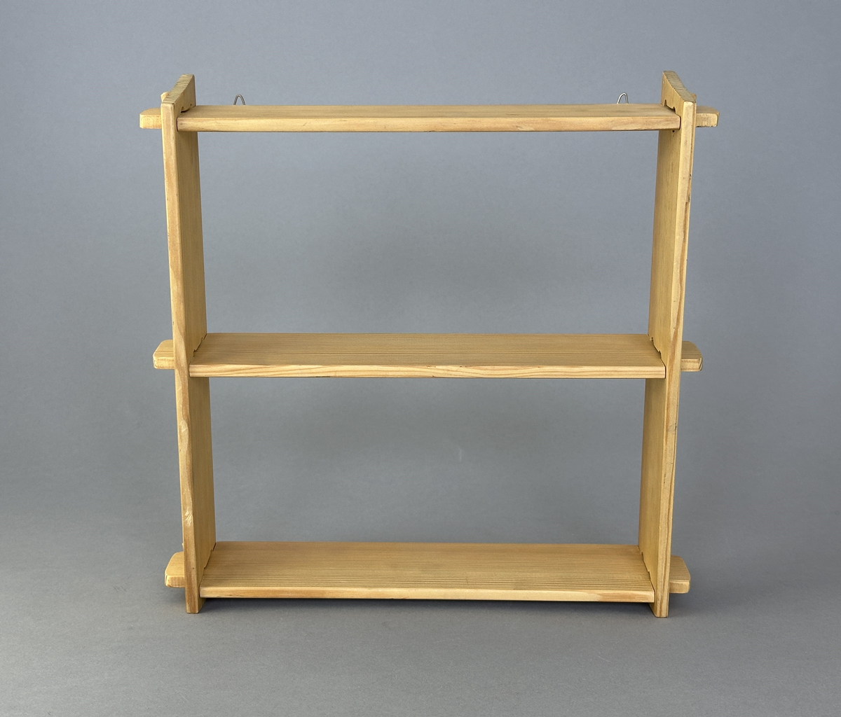 Hylla av trä med tre hyllplan för upphängning på vägg.