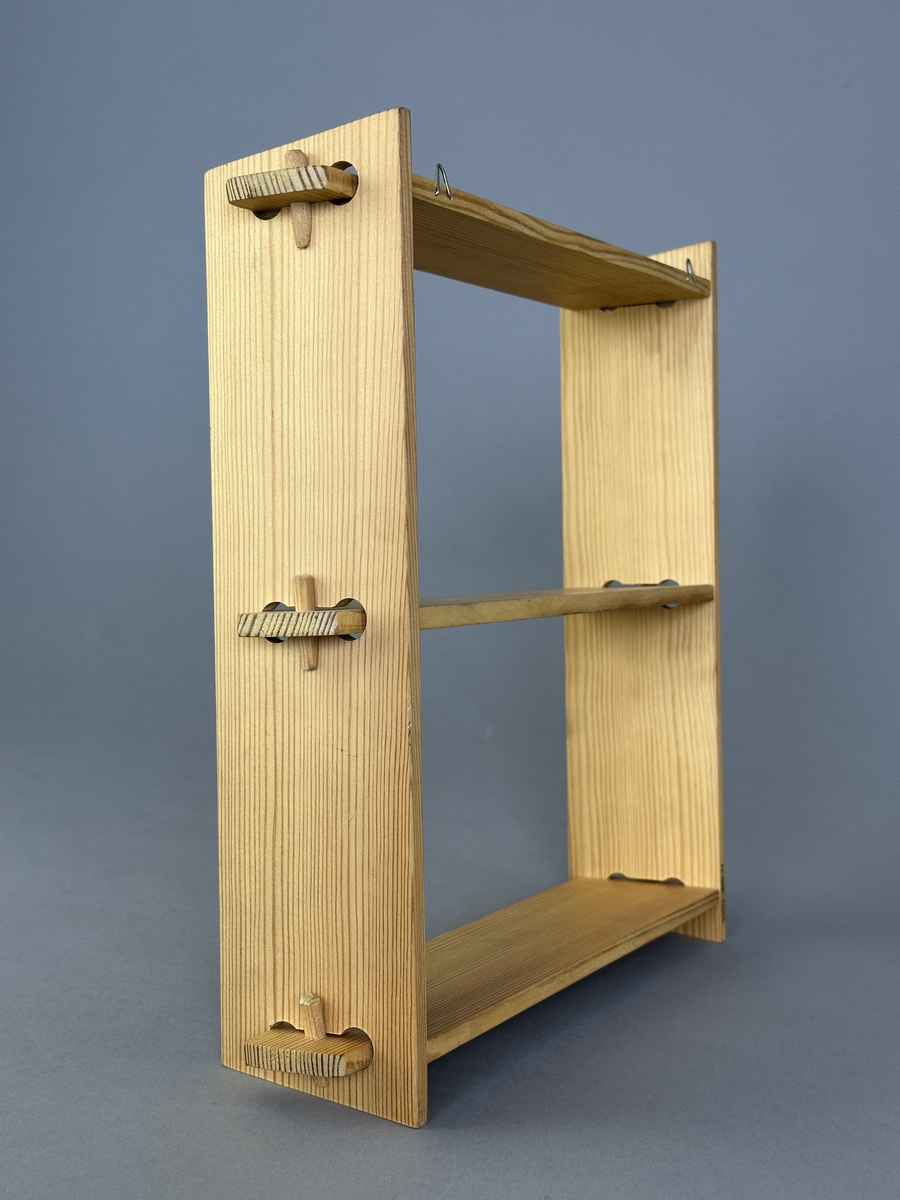 Hylla av trä med tre hyllplan för upphängning på vägg.