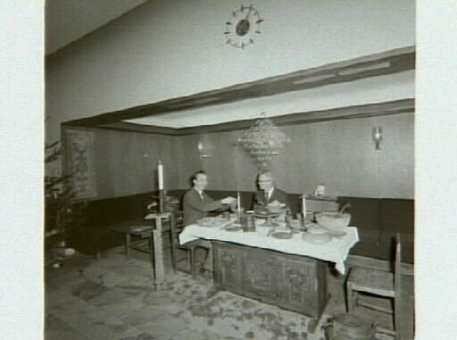Julbord i allmogestil på Göteborgs bank. Bröd, gröt, korvar och potatis är uppdukat i skålar och fat av trä. Även tallrikar, stop, bägare och andra föremål är av trä. På golvet står en stor kopparpanna och till höger en höj- och sänkbar piedestal. Över bordet hänger en "oro", en sorts takkrona av halm eller vass. Bild 1: Museichef Bengt-Arne Person t h slår upp i snapsglasen åt bankdirektör H Reich t v. Bild 2: Fyra ungdomar kring julbordet.
(Se även bildnr G1036-1037.)

Oroar tillverkades som skydd mot onda andar och hängdes förr över bordet eller barnens sängar. Man gjorde också särskilda kronor till bröllop. Bäst var att hänga upp oron i ett kvinnohår så den kom i rörelse vid minsta drag och därmed snärjde in eventuella onda andar. Oron dekorerades på olika sätt med vad man råkade ha, t ex tygbitar, garn eller papper. I Finland kallas denna hantverkstradition för Himmeli.