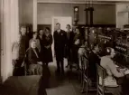 Piteå telefonstation år 1932. Telefonsal. Gruppfoto. Telegrambud Sven Holmberg. K.E. Hertlander, rikstelefonist H. Sundqvist (sittande), telegrafexpiditör  A. Holmgren, landstelefonist R. Ekberg, lokaltelefonist G. Bergman, Telegrafkommisarie S.A. Hydén, lokaltelefonist E. Forsman, rikstelefonist J. Engström, rikstelefonist I. Bucht, rikstelefonist A. Pettersson, lokaltelefonist J. Berglund, lokaltelefonist E. Ekberg.