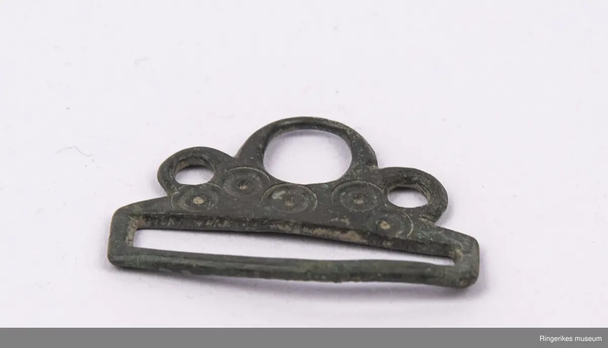 Spenne, antakelig beltespenne, av metall med sirkeldekor.