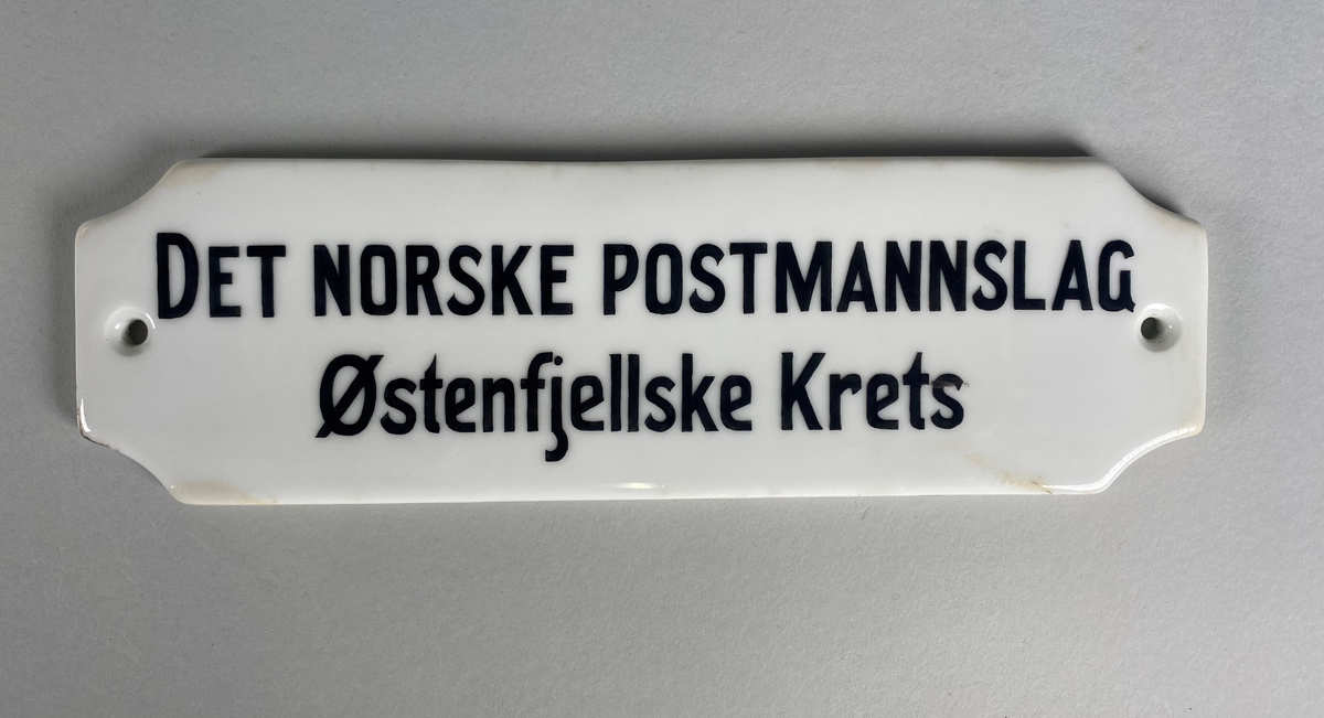 Skilt i porselen med svart tekst. På baksiden er skiltet stemplet fra produsent med nummer 456.