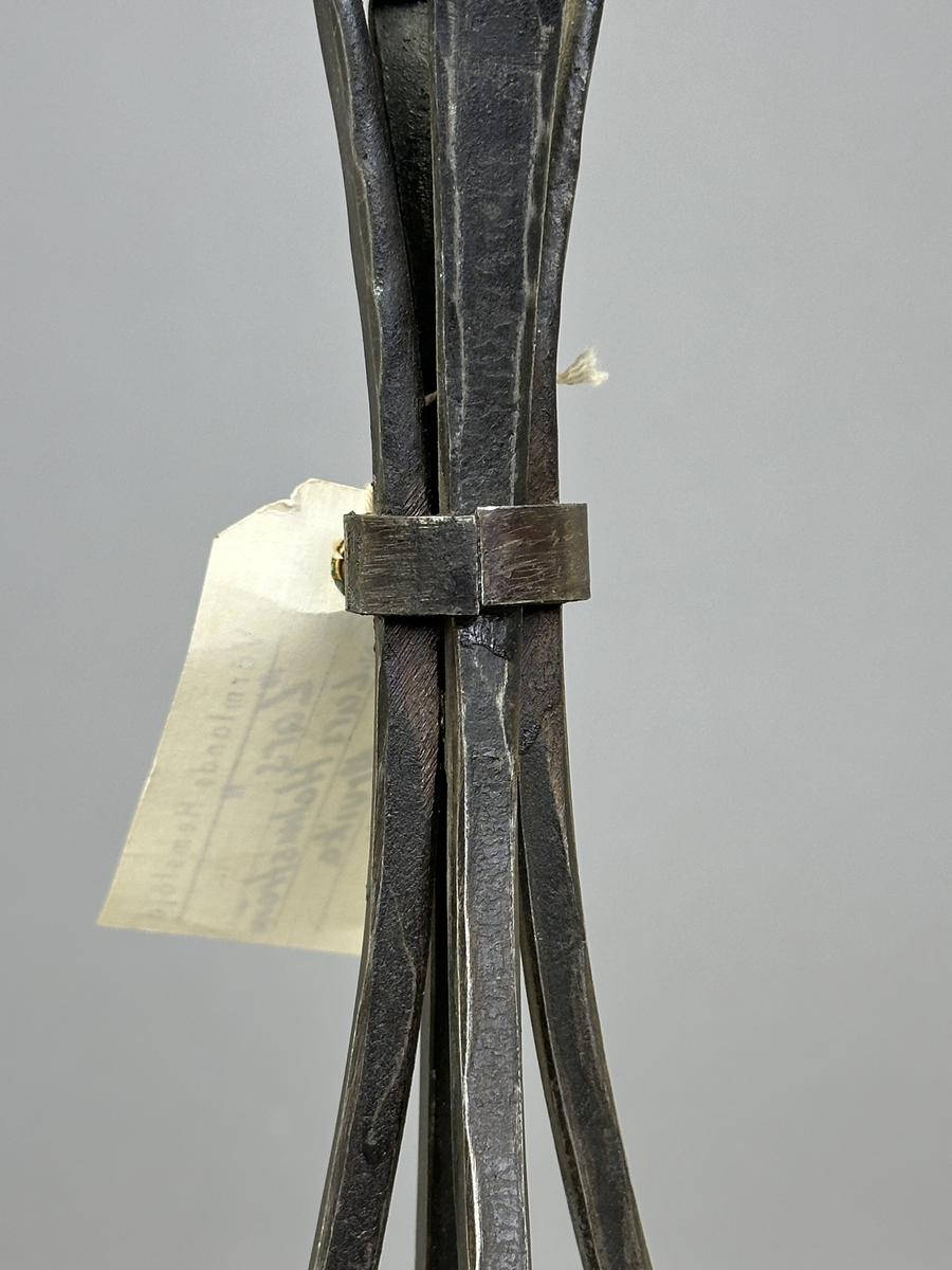 Ljusstake "Lars" av järn för ett ljus. Fyra fyrkantsstänger har sammanfogats i ena änden med en ljusmanschett och en bit nedanför hålls de ihop av en ring.