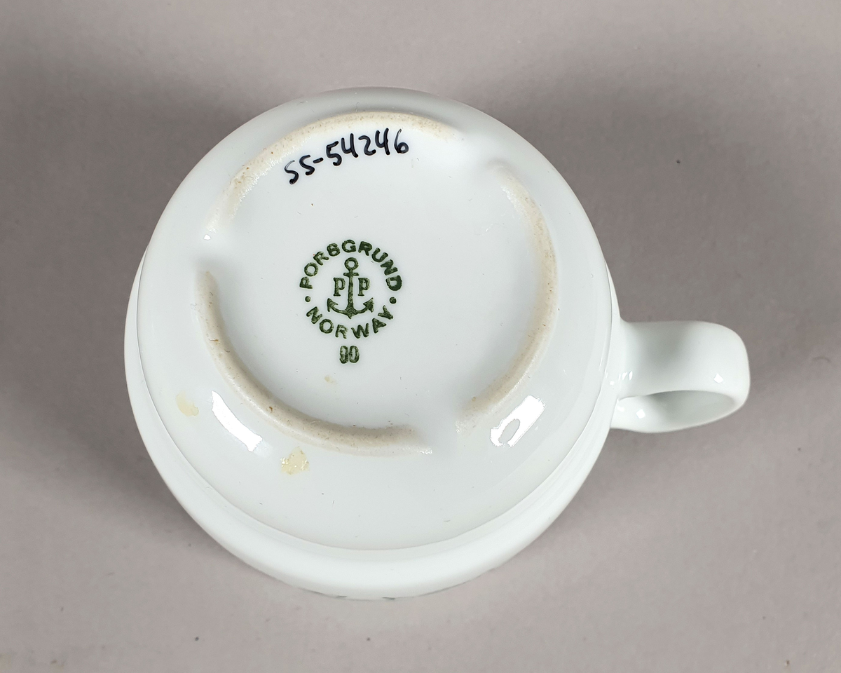 Hvit kaffekopp av porselen, med grønt bladmønster langs kanten og turistforeningens logo fra perioden etter 1988.