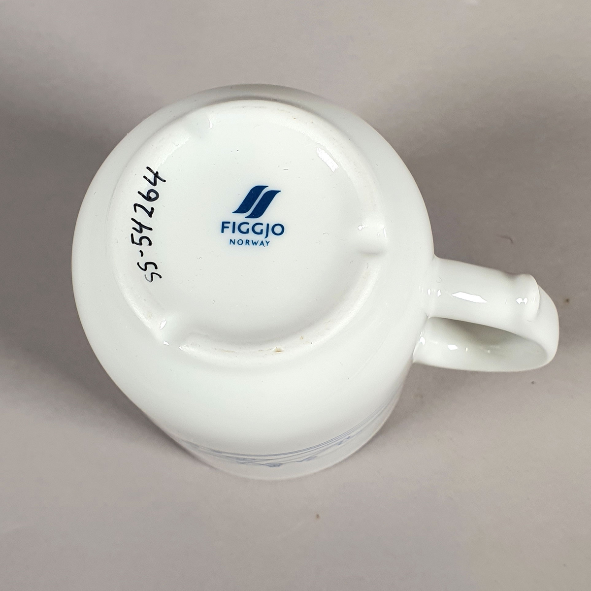Hvit kopp av porselen, med med blått dekor (fjellmotiv) rundt korpus, og turistforeningens logo fra 1988