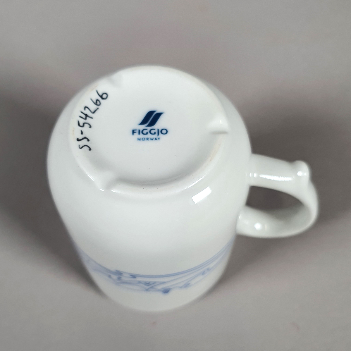 Hvit kopp av porselen, med med blått dekor (fjellmotiv) rundt korpus, og turistforeningens logo fra 1988
