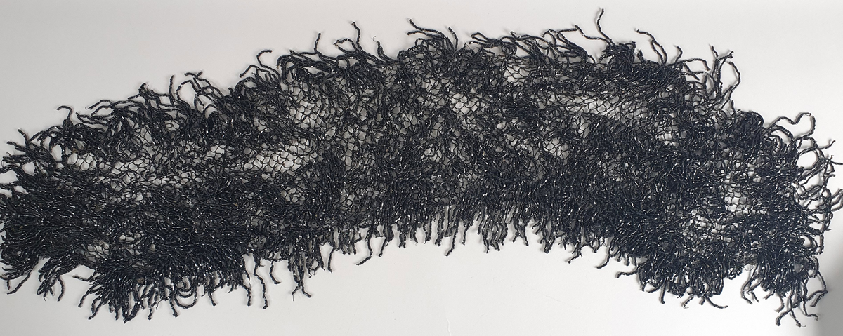 Oval eske med lokk. På lokket er det malt hus langs en elvebredd med båter i forgrunnen. Trær i bakgrunnen. I eske ligger det et nett av perler.  