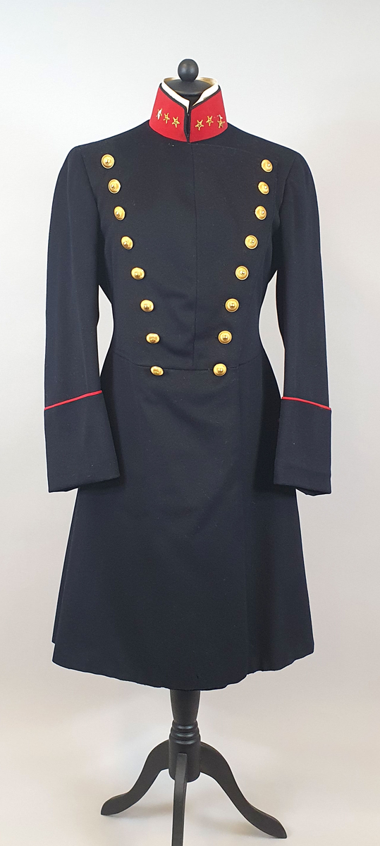 Mørkeblå uniformsfrakk av ull med rød krage med tre stjerner på hver side (kapteinsgrad). Løskrage av kartong på innsiden av kragen. Dobbeltspent med 8 gullknapper på hvert forstykke som er vattert. Frakken er innsvinget i livet og har splitt på ryggen med knapper og røde kantbånd. Rødt kantbånd på mansjettene. Svart fôr av bomull.