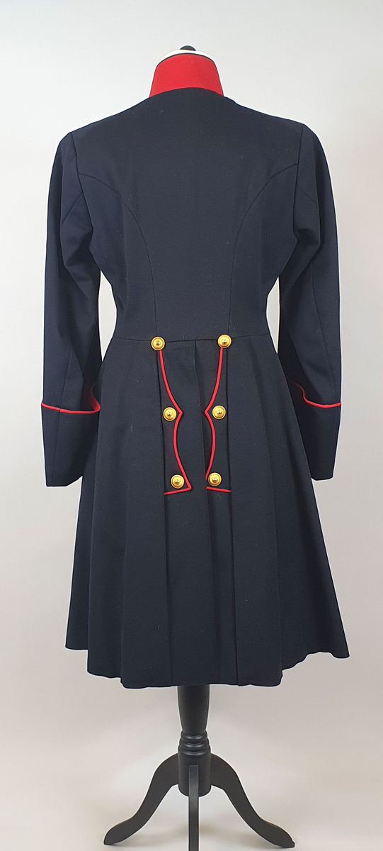 Mørkeblå uniformsfrakk av ull med rød krage med tre stjerner på hver side (kapteinsgrad). Løskrage av kartong på innsiden av kragen. Dobbeltspent med 8 gullknapper på hvert forstykke som er vattert. Frakken er innsvinget i livet og har splitt på ryggen med knapper og røde kantbånd. Rødt kantbånd på mansjettene. Svart fôr av bomull.