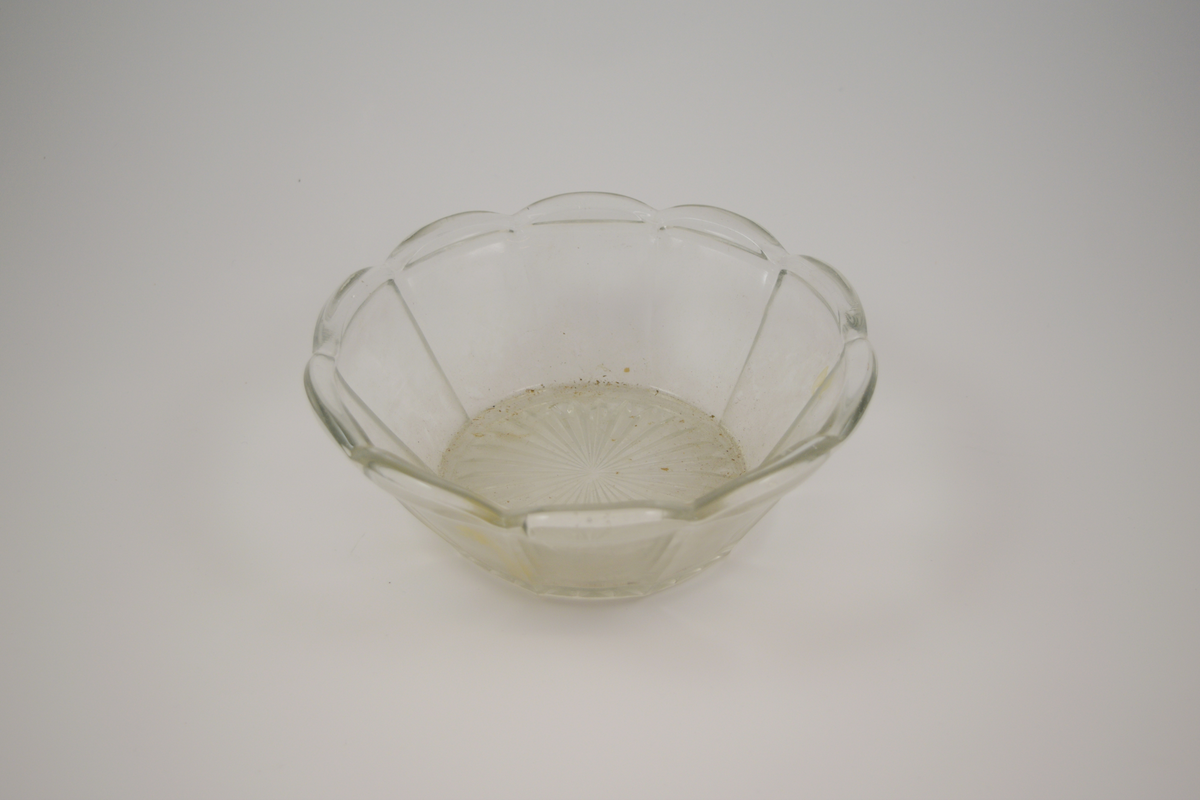 13 stk. runde glass fat av 5 ulike typer. To typer glassasjetter: 2 stk. med fasetter som minner om kronblader og bølgete kant, 4 stk. rette med forhøyet kant ytterst. Tre typer glasskåler: 1 stk. med fasetter som minner om kronblader og bølgete kant. 3 stk. med fasetter i bunnen, men rett kant, 1 stk. med kløverdekor i bunnen og rett kant. En type glassbolle med fasetter som minner om kronblader og bølgete kant.