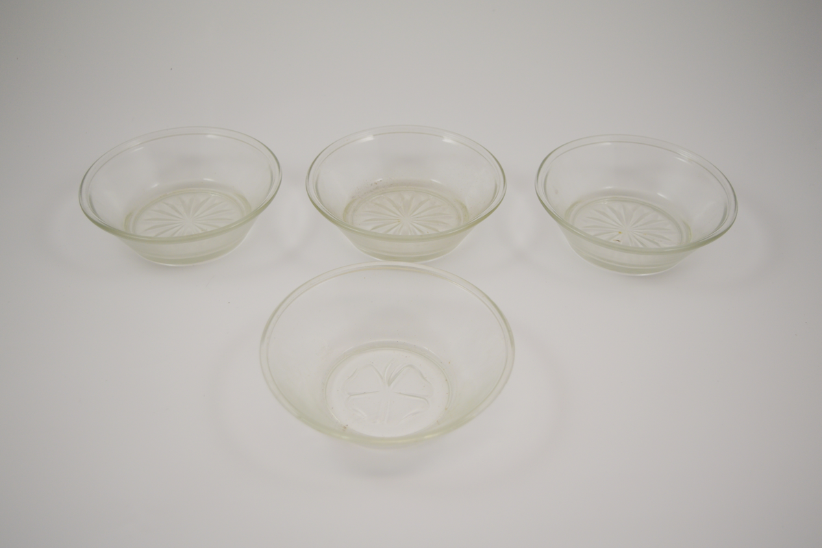13 stk. runde glass fat av 5 ulike typer. To typer glassasjetter: 2 stk. med fasetter som minner om kronblader og bølgete kant, 4 stk. rette med forhøyet kant ytterst. Tre typer glasskåler: 1 stk. med fasetter som minner om kronblader og bølgete kant. 3 stk. med fasetter i bunnen, men rett kant, 1 stk. med kløverdekor i bunnen og rett kant. En type glassbolle med fasetter som minner om kronblader og bølgete kant.