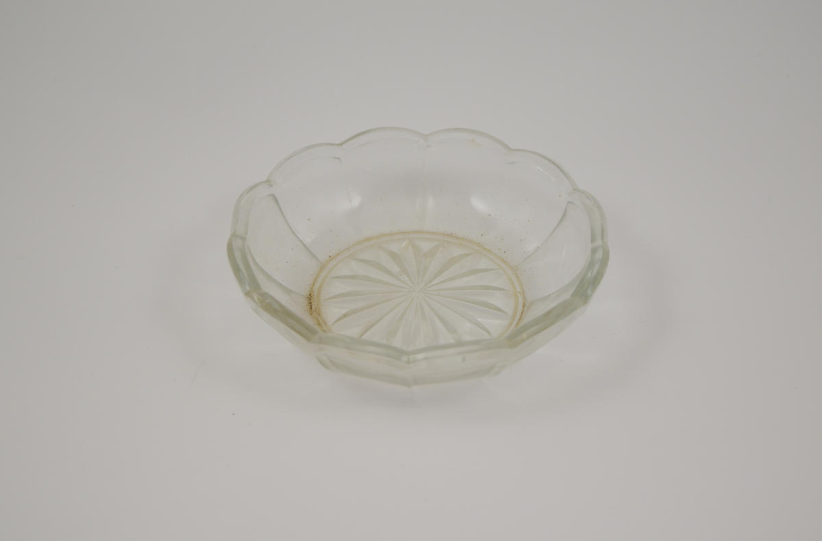 13 stk. runde glass fat av 5 ulike typer. To typer glassasjetter: 2 stk. med fasetter som minner om kronblader og bølgete kant, 4 stk. rette med forhøyet kant ytterst. Tre typer glasskåler: 1 stk. med fasetter som minner om kronblader og bølgete kant. 3 stk. med fasetter i bunnen, men rett kant, 1 stk. med kløverdekor i bunnen og rett kant. En type glassbolle med fasetter som minner om kronblader og bølgete kant.