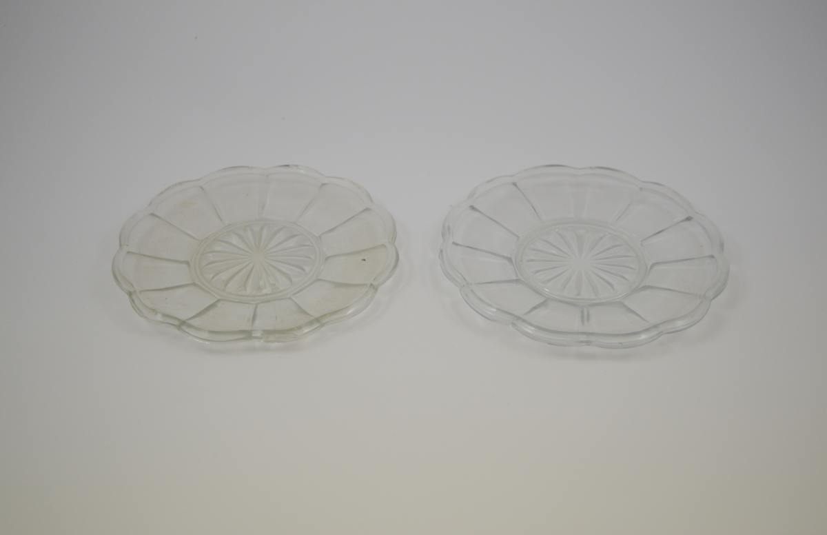 13 stk. runde glass fat av 5 ulike typer. To typer glassasjetter: 2 stk. med fasetter som minner om kronblader og bølgete kant, 4 stk. rette med forhøyet kant ytterst. Tre typer glasskåler: 1 stk. med fasetter som minner om kronblader og bølgete kant. 3 stk. med fasetter i bunnen, men rett kant, 1 stk. med kløverdekor i bunnen og rett kant. En type glassbolle med fasetter som minner om kronblader og bølgete kant.
