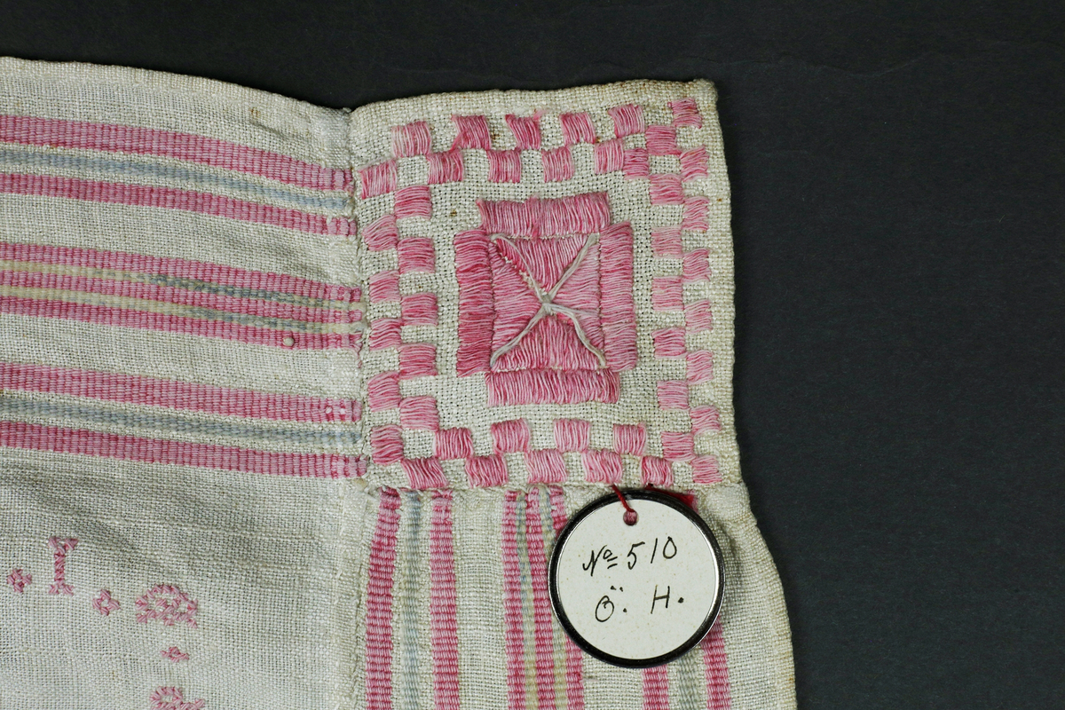 Kvadratiskt halskläde av hellinne. Bård i inslagsrips. Broderi i nedre vänstra hörnet och märkt MPD 1832. Insydd ruta i nedre vänstra hörnet. Broderier i rätlinjig plattsöm och korssöm.