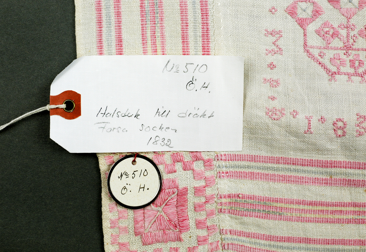 Kvadratiskt halskläde av hellinne. Bård i inslagsrips. Broderi i nedre vänstra hörnet och märkt MPD 1832. Insydd ruta i nedre vänstra hörnet. Broderier i rätlinjig plattsöm och korssöm.