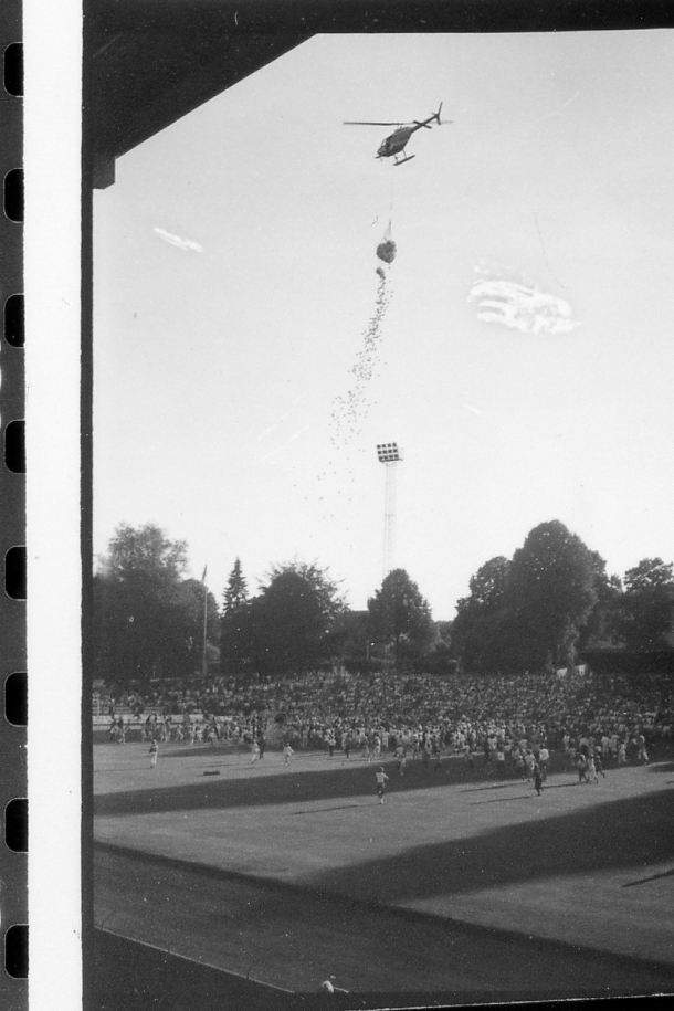 Halmstad, Örjans vall. Prestigederbyt "bäst i stan"- HBK mot Halmia, 18 juli 1984. Foto 1 och 2 (14A-15A) Arla bjöd på gräddtårta. Foto 3, 4 och 5 (16A-18A) Helikopter släppte ner bollar till barnen. Foto 6, 7, 8, 9, 10 (19A-23A) Helikopter släppte ner bollar till barnen. Foto 11 och 12 (24A-25A) Helikopter släppte bollar till barnen. Foto 13, 14 och 15 (26A-28A) Arla luftballong. Foto 16 och 17 (30A-31A) Arla Jet delade ut plastpåsar med reklam.