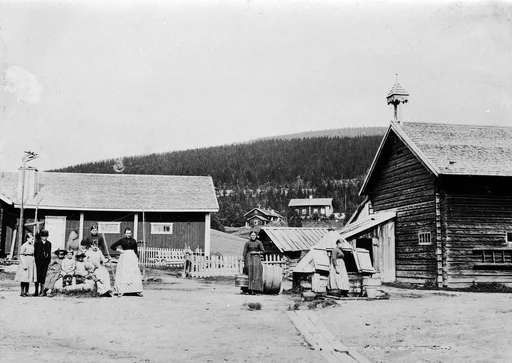 Kvinner og barn på tunet, brønnshus, vannbæring, rakerive. Onn.
