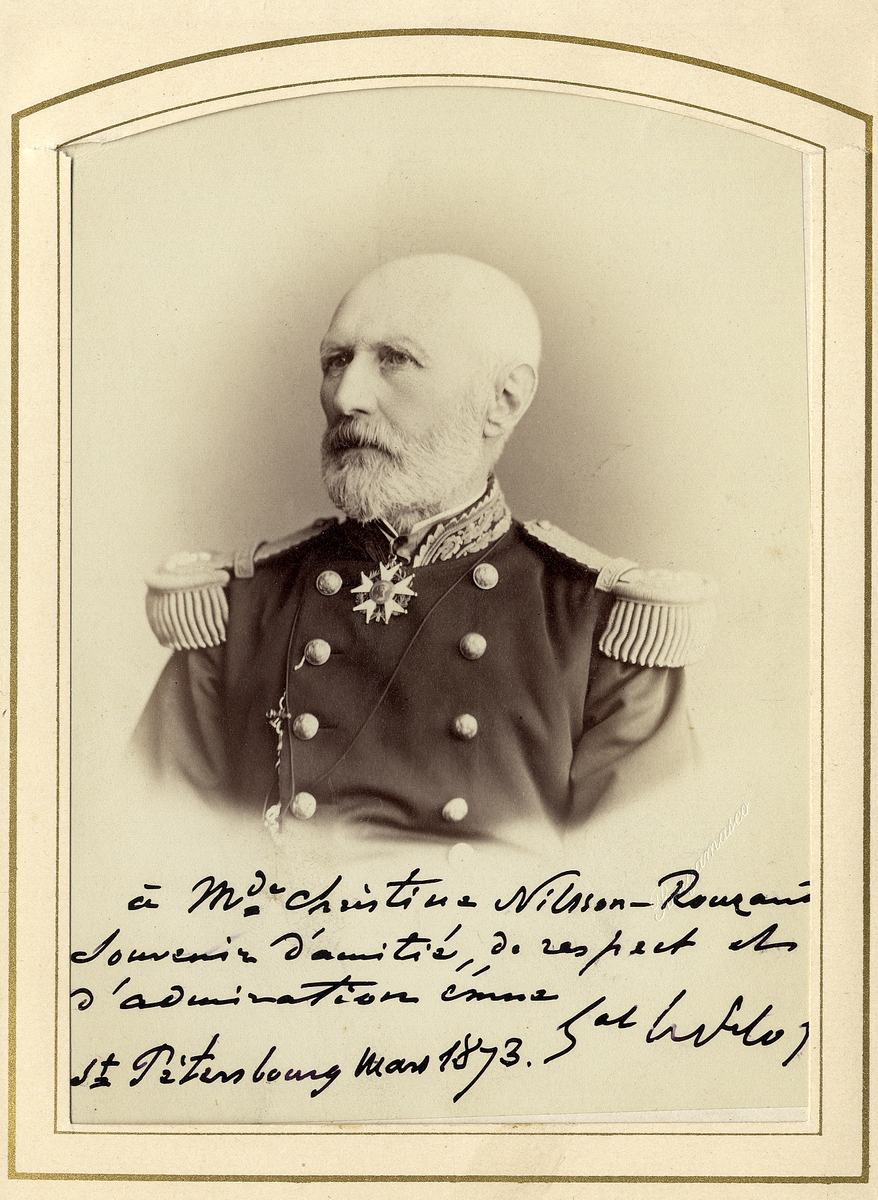 Porträttfoto av en äldre man i paraduniform med guldstickad krage, epåletter och en orden.
Dedikation på franska nedtill: "À Mde Christina Nilsson-Rouzau, Souvenir d'amitié, de respect et d'admiration....(oläsligt).
St Petersbourg, Mars 1873".
Bröstbild, halvprofil. Ateljéfoto.
Inskrivet i huvudbok 1951.
