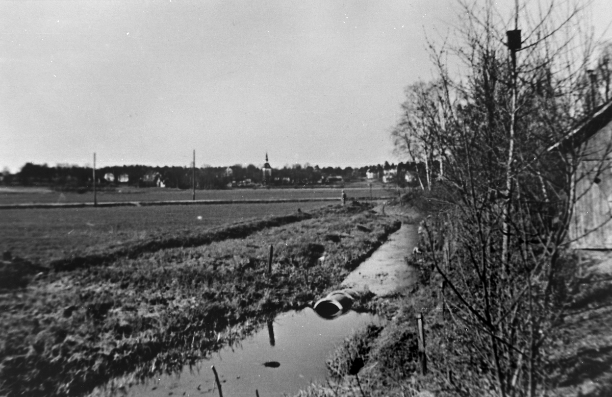 Sjöängen år 1925.
 ; BHF Studiecirkel vt 2016:
Bilden tagen ungefär från Helgarögränd mot kyrkan. Rågfeldts uthus t.h. i förgrund. Tidigare cykelväg ovanpå dräneringskulverten syns horisontellt i bild.