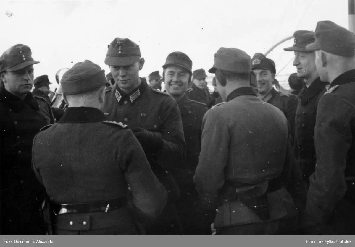 Befal og soldater ved 13. kompani av grenaderregiment 193 (13./GR 193) ombord i mindre fartøy i Vadsø havn. Trolig under overføring fra Vadsø til Murmanskfronten i april 1942.