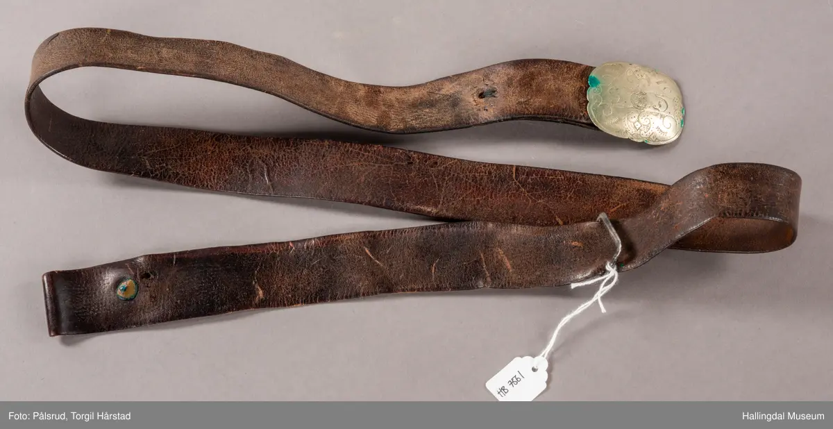 Skinnbelte med beltespenne. Gravert på beltespennen: "S.E.D."