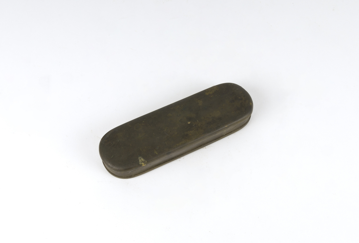 Dåse, tobakksdåse. Avlang oval snusdåse av messing med avrundede hjørner. Har en påsatt og påklinket utenpåliggende bunn og utenpåliggende, hengslet lokk.
