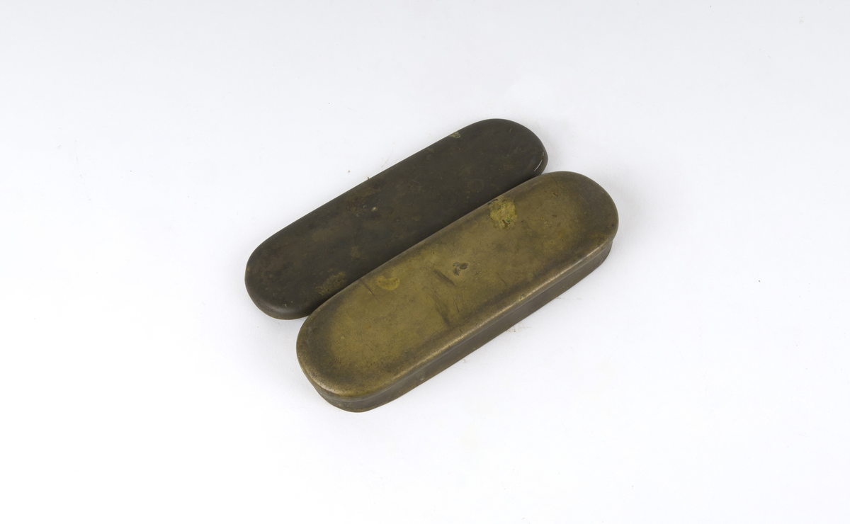Dåse, tobakksdåse. Avlang oval snusdåse av messing med avrundede hjørner. Har en påsatt og påklinket utenpåliggende bunn og utenpåliggende, hengslet lokk.