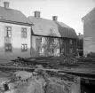 Ågatan 41 och 39 i Linköping. I början av 1950-talet skulle husen komma att monteras ned för nya placeringar i friluftsmuseet Gamla Linköping som Spegelmakaregården respektive Jungfru Lovisas gård. Vid fototillfället 1938 hade man för första gången på evigheter -sannolikt någonsin- fri sikt mot husen på sina ursprungliga platser. Personal från Östergötlands museum passade på att dokumentera dem i samband med saneringsarbeten i det framförliggande kvarteret Borgaren.