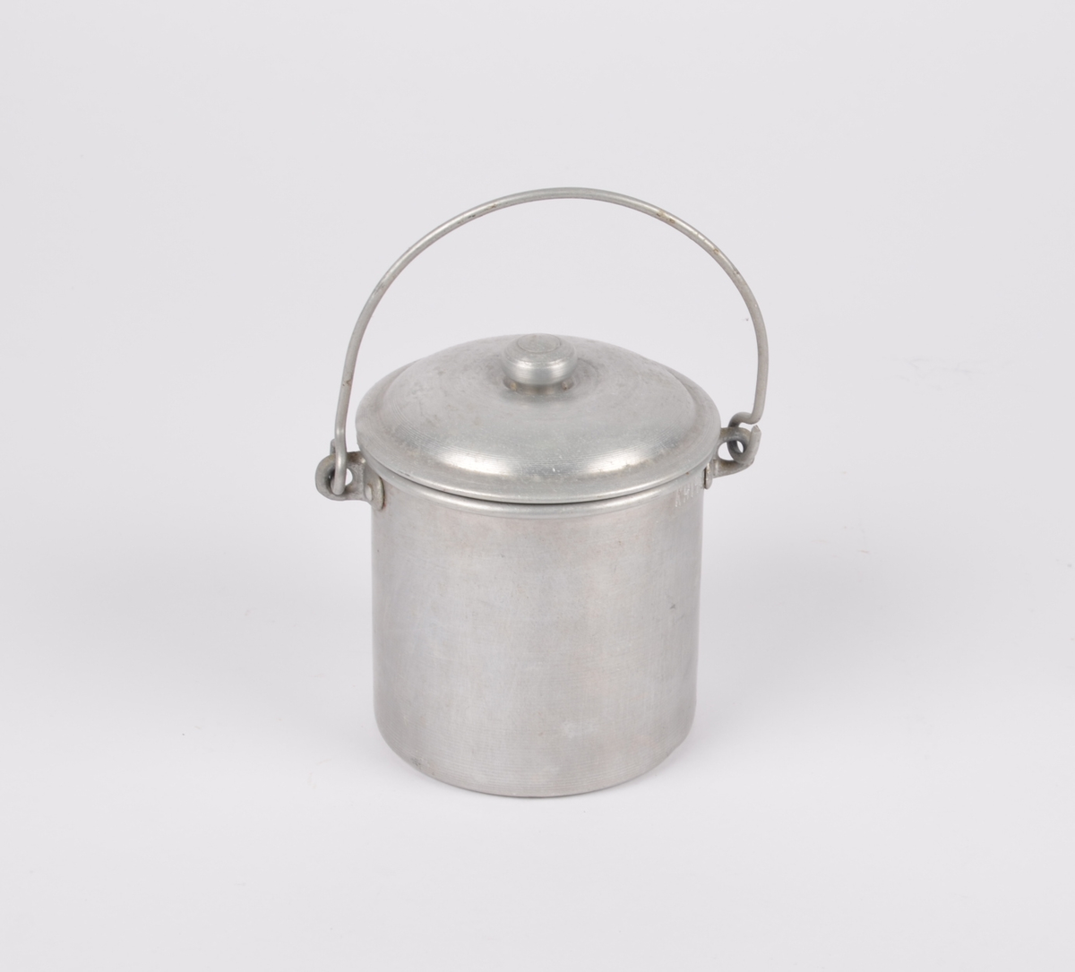 Sylindrisk fløtespann i aluminium med hank. Tilhørende sirkulært lokk med liten knopp.