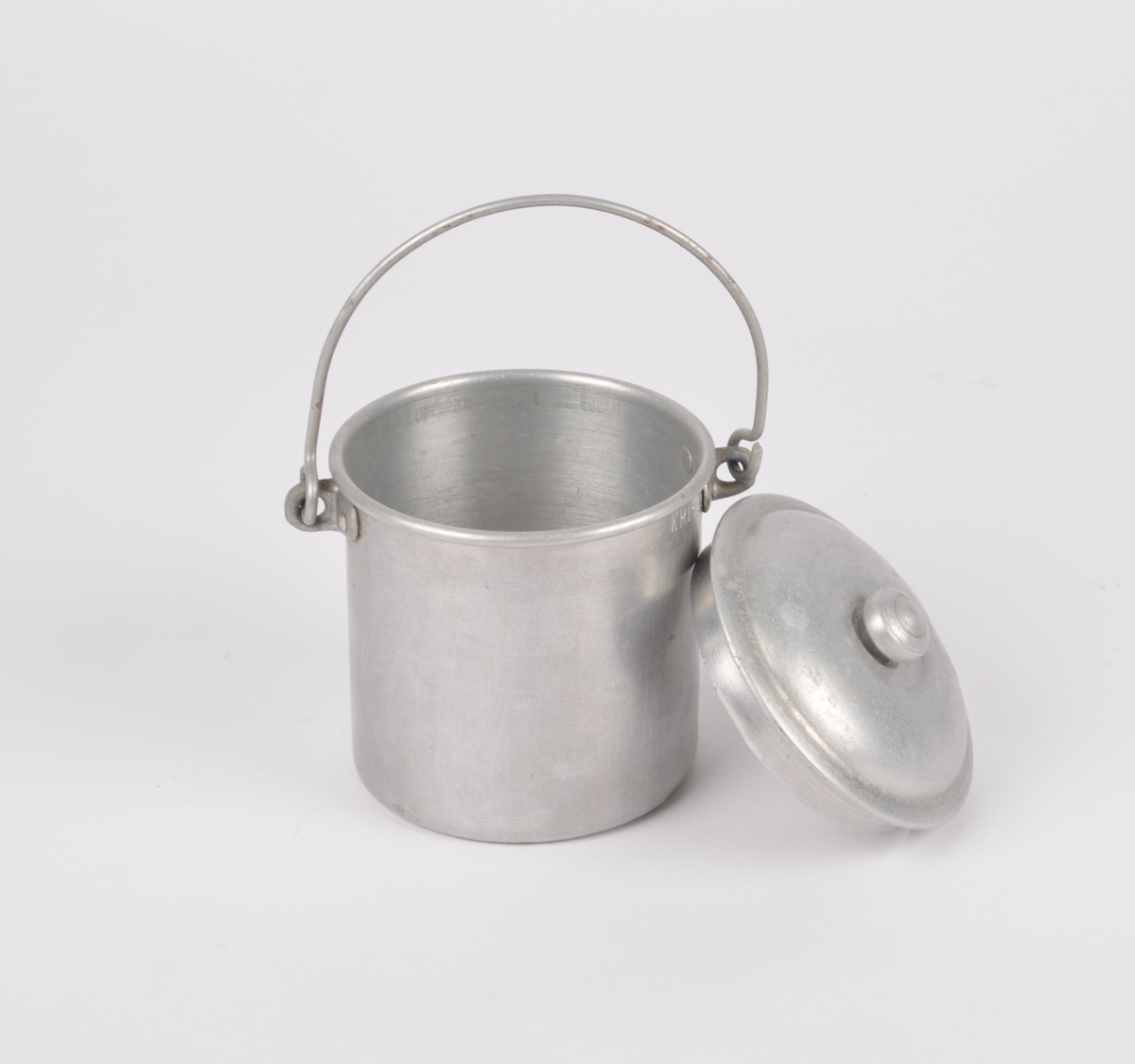 Sylindrisk fløtespann i aluminium med hank. Tilhørende sirkulært lokk med liten knopp.